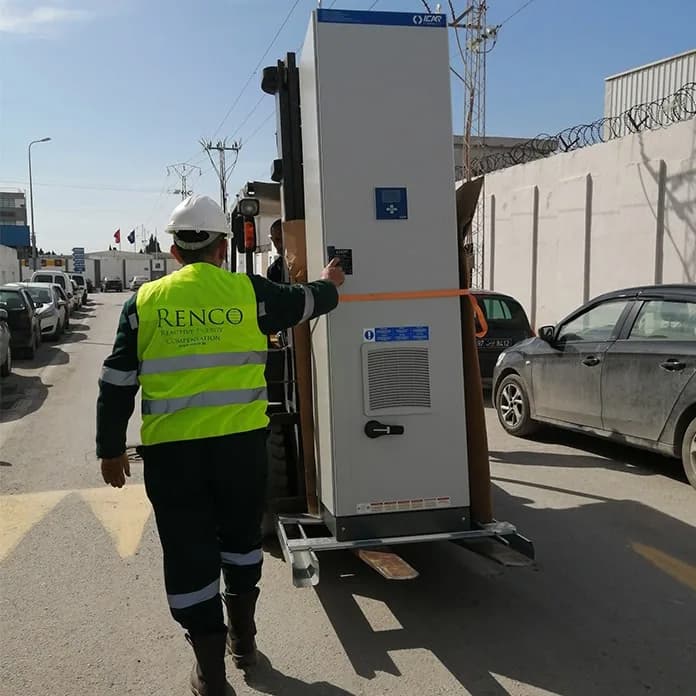 Renco technician in a hi-vis vest moving a capacitor bank cabinet along the street