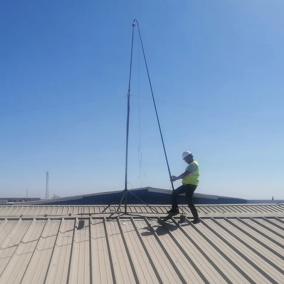 Technician raising a lightning rod mast on an industrial roof