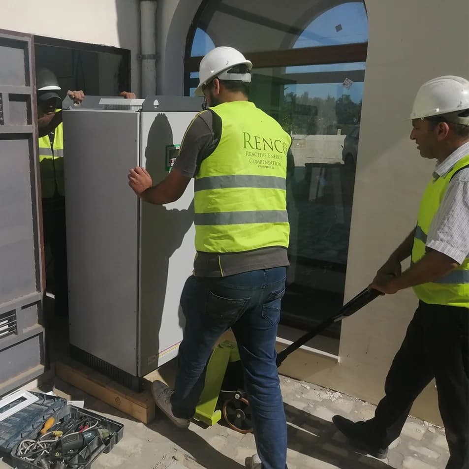 Two Renco technicians putting a voltage stabiliser cabinet in place